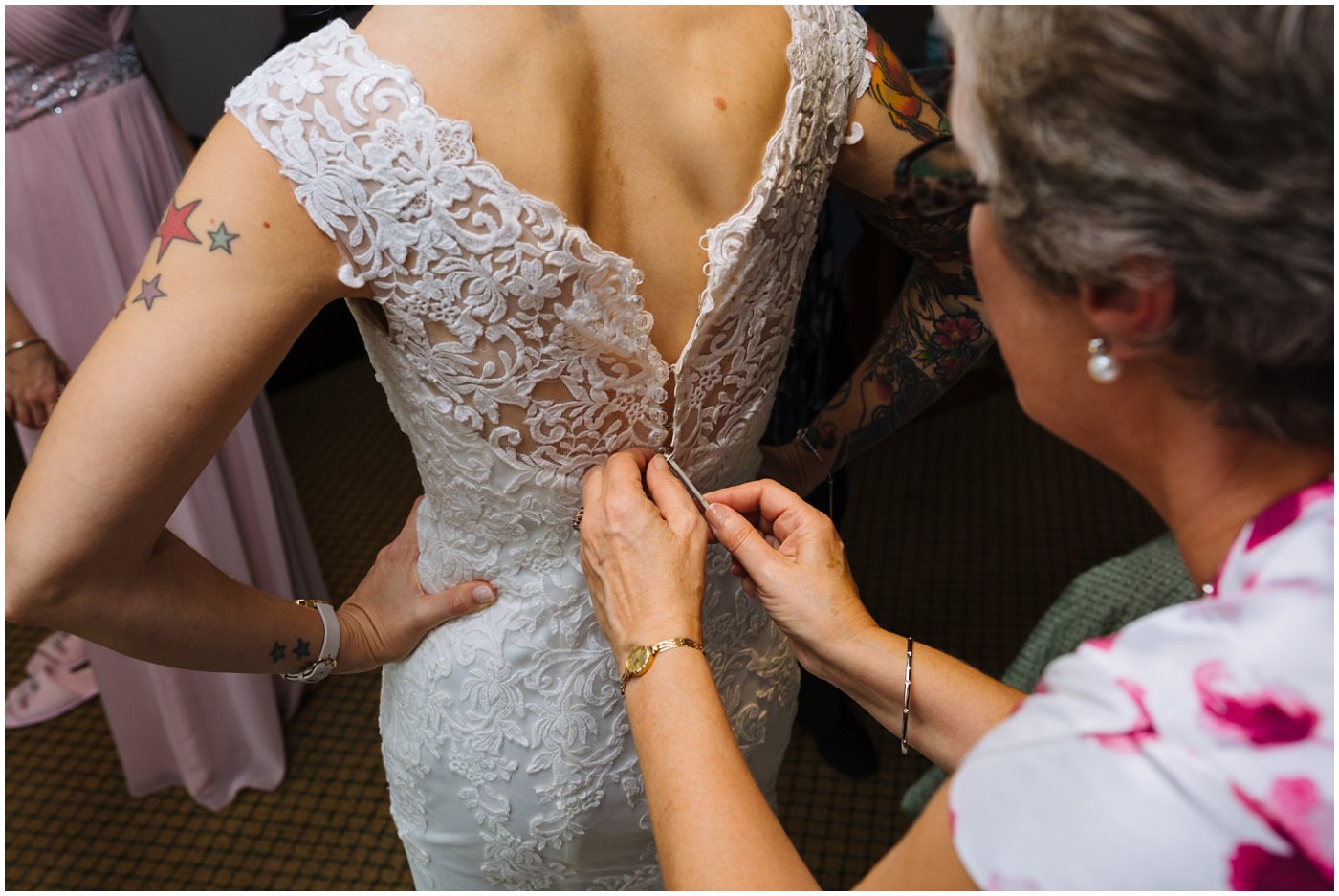 mother of the bride fastens wedding dress