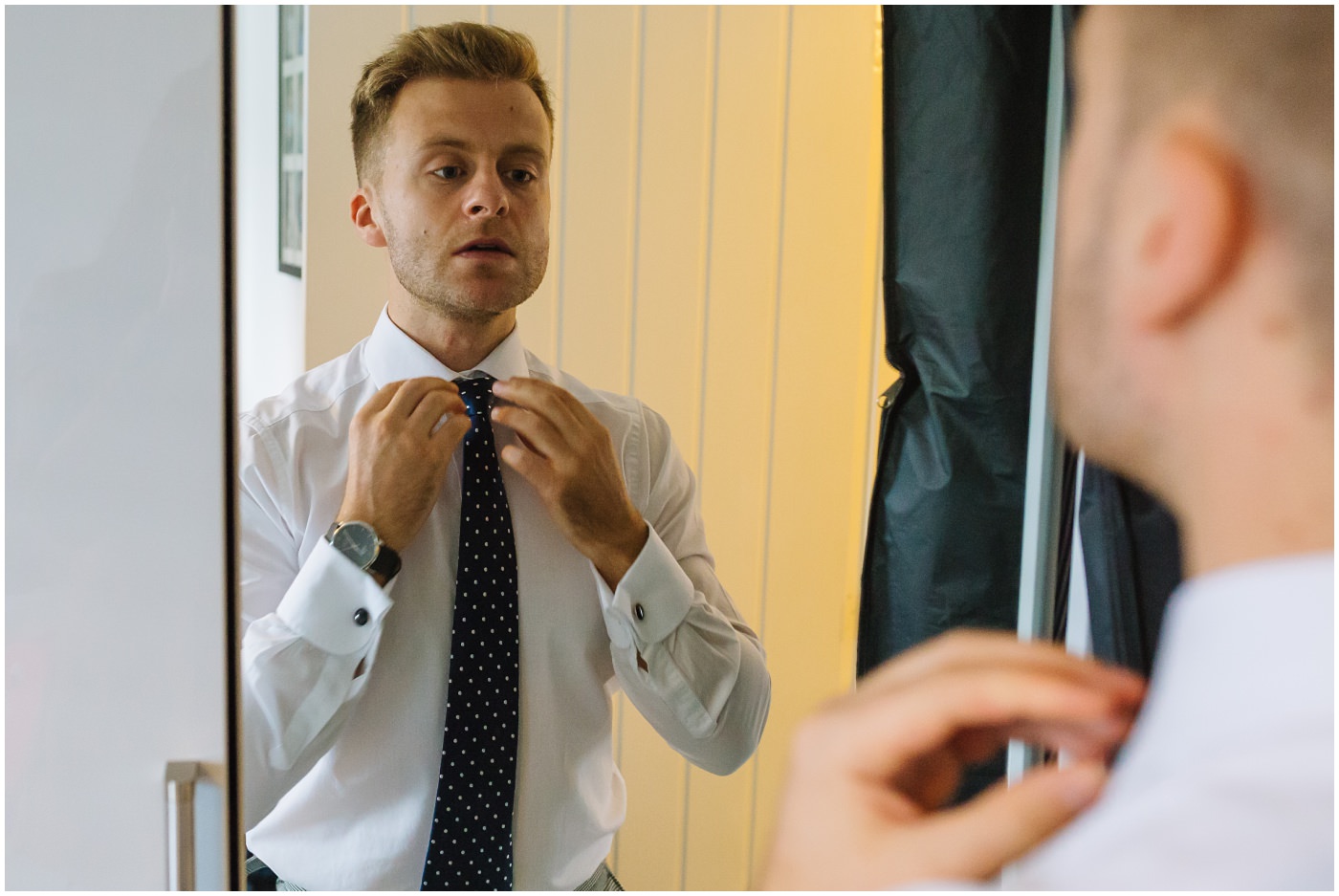 groom straightens tie in mirror