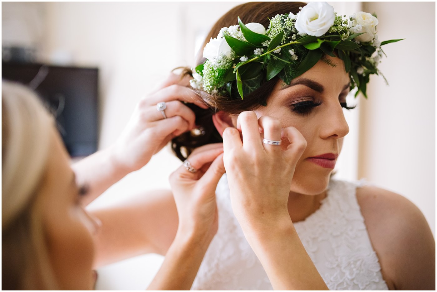 bridesmaid helps bride with ear rings