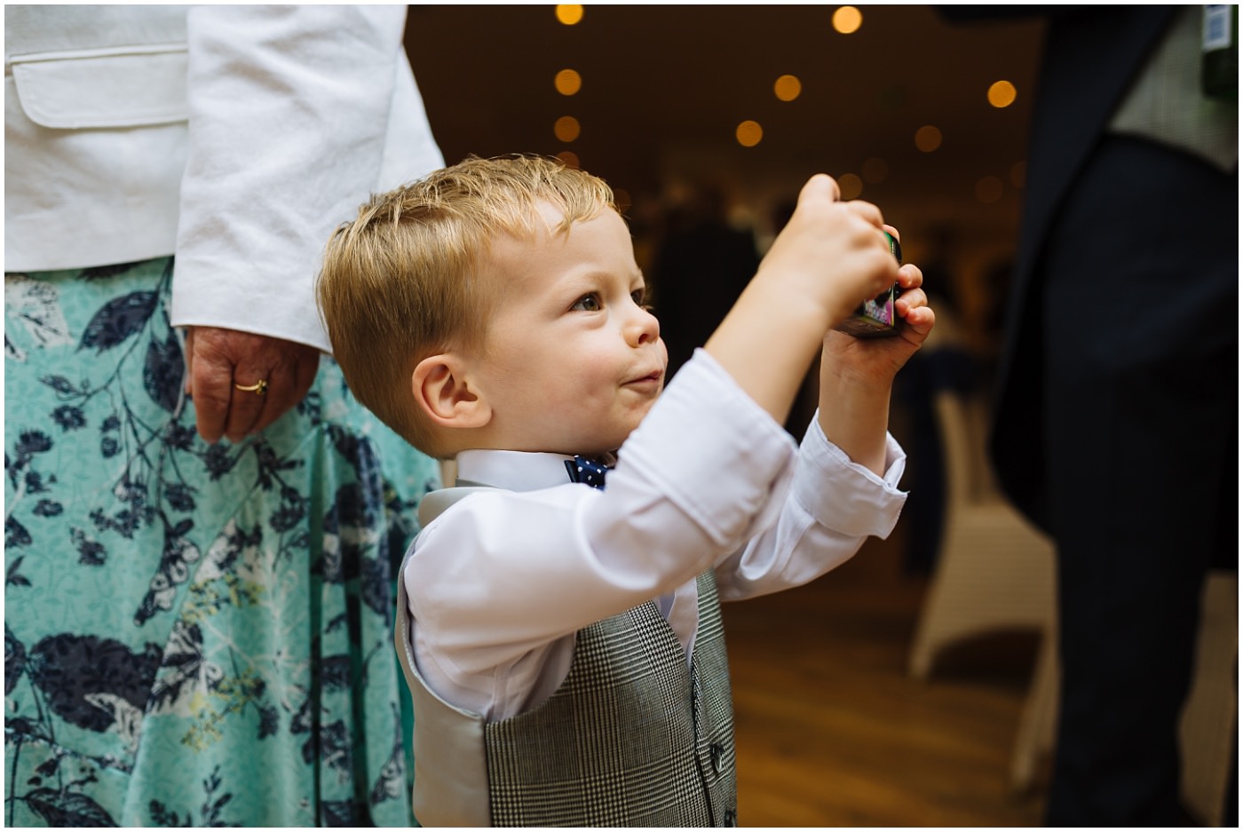 little boy plays with disposable camera at a wedding