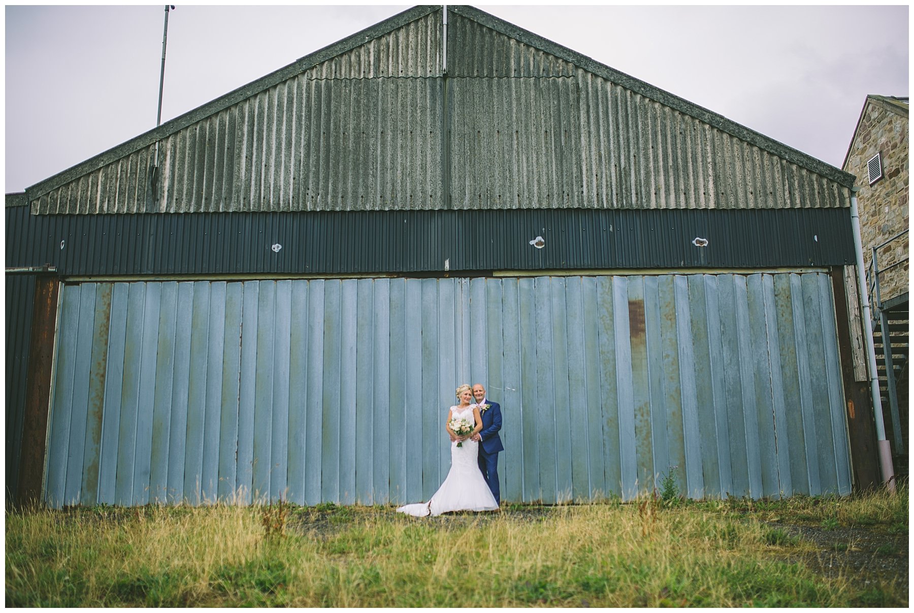 bride and groom stand in front of the iconic hanger at beeston manor