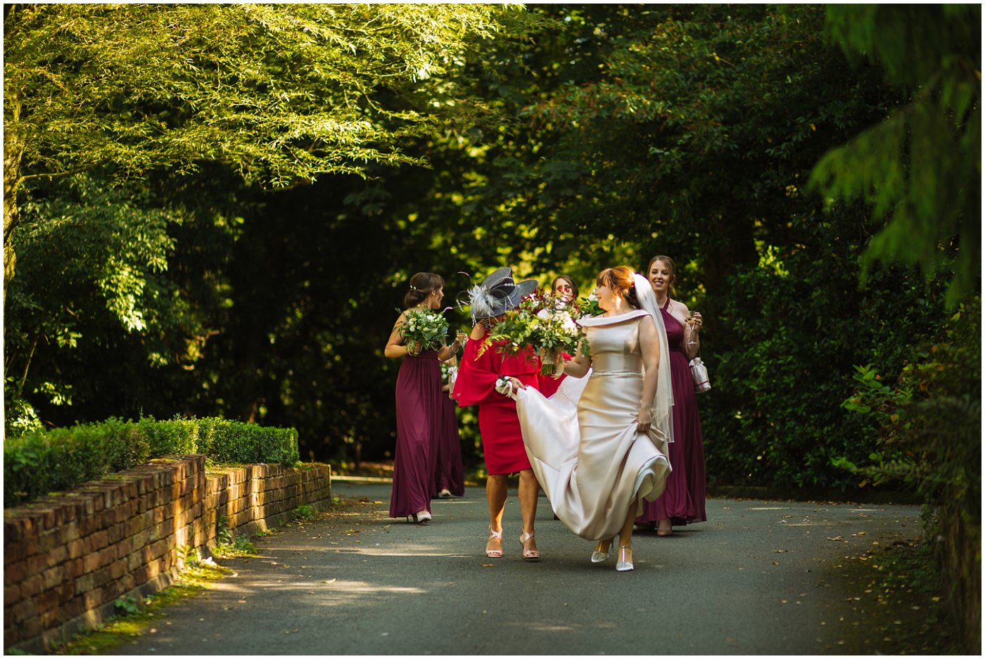 bride and her bridesmaids walk through the grounds of samlesbury hall